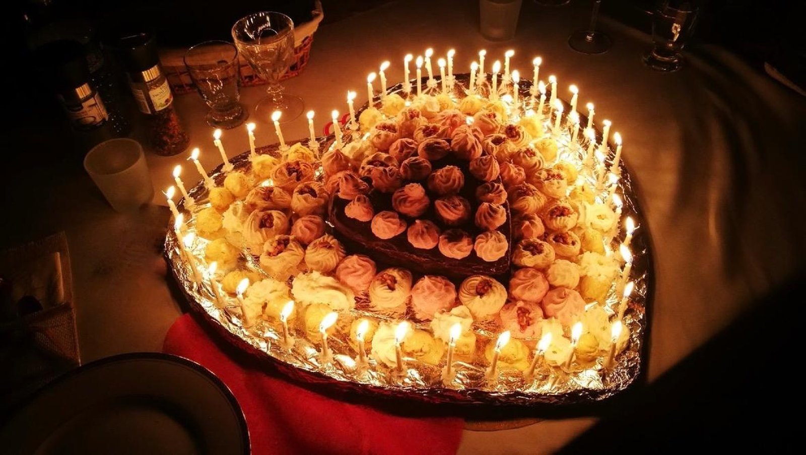 Gâteau d'anniversaire en forme de cœur — cupcakes et bougies allumées