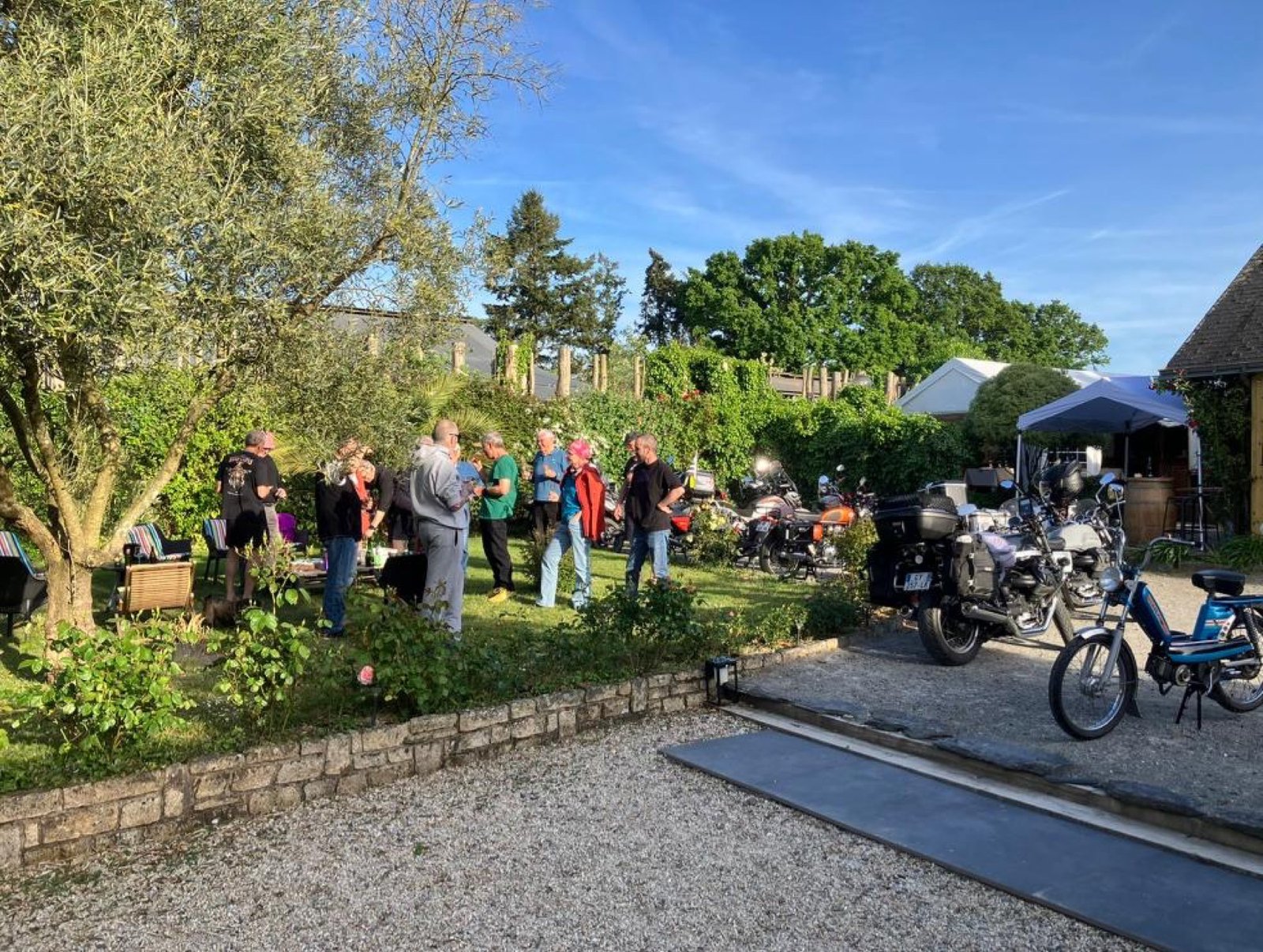 Club de motards rassemblé dans le jardin, motos garées